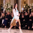 Model walking a fashion runway before an audience, illustrating the designers and creatives behind the best and worst dressed UK celebrities