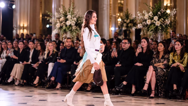 Model walking a fashion runway before an audience, illustrating the designers and creatives behind the best and worst dressed UK celebrities