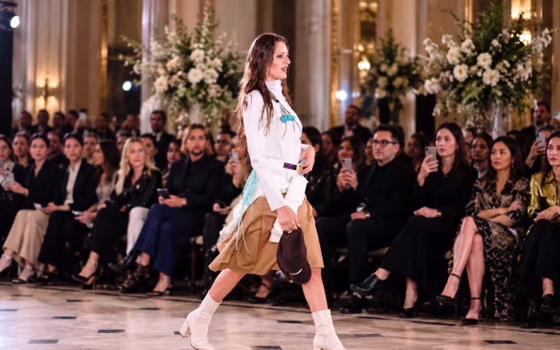 Model walking a fashion runway before an audience, illustrating the designers and creatives behind the best and worst dressed UK celebrities